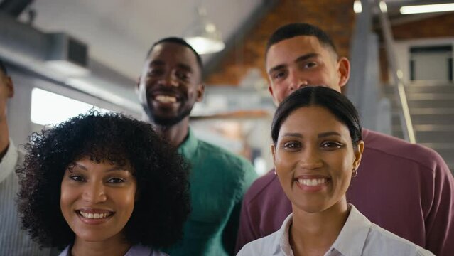 Close up portrait shot of smiling multi-cultural business team in modern open plan office together - shot in slow motion