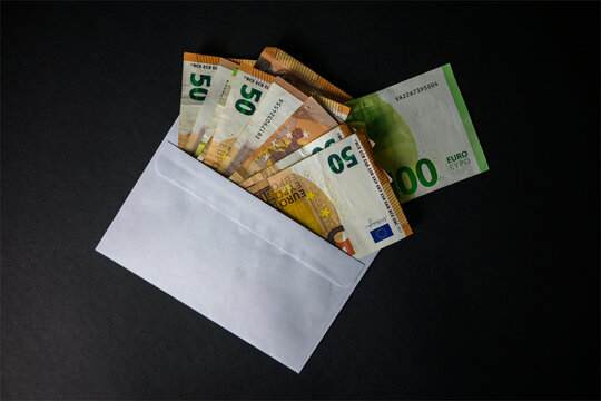 euro money sticking out of the envelope on a black background - top view
