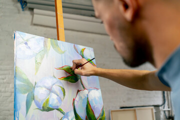 in an art studio a painting with flowers the artist sitting the details on the painting with red...