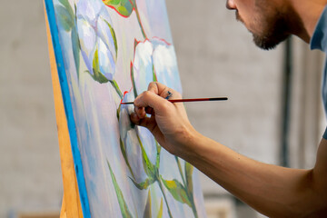 in an art studio a painting with flowers the artist sitting the details on the painting with red...