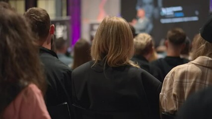 Young adults engage in discussion at startup event, exchanging ideas in conference hall. Energetic youth congregate for entrepreneurship seminar, immersed in startup culture at business incubator.
