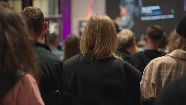 Young adults engage in discussion at startup event, exchanging ideas in conference hall. Energetic youth congregate for entrepreneurship seminar, immersed in startup culture at business incubator.