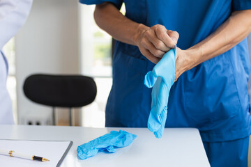doctor is wearing blue rubber gloves prevent direct contact with patient because virus may be traced to patient body and medical rubber gloves also help prevent virus from being transmitted to patient