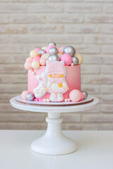 Cute gradient pink birthday cake with gingerbread little girl and bunny, with a pile of chocolate silver balls on the top. Ideal gift for a child
