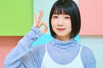 okのハンドサインをする若い女性とカラフルな背景