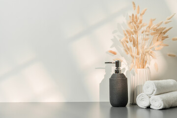 Soap dispenser and spa towels on white background in shadow