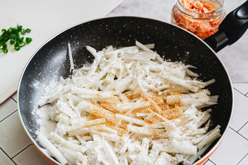 フライパンで焼く大根の千切りに調味料を加える