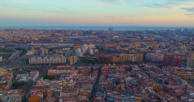 Aerial view of Barcelona urban skyline at sunset. Catalonia, Spain. Drone flies towards the sea