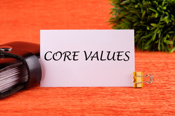 CORE VALUES word written on a white card near the business card holder in black on an orange...
