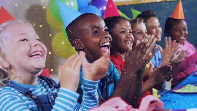 Animation of gold confetti falling over happy diverse children clapping at birthday party