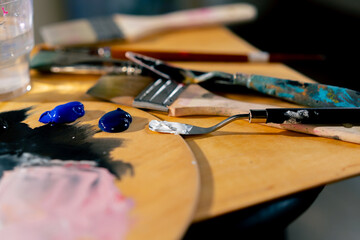 close-up in an art workshop there is a palette on stool palette knife a glass of solvent