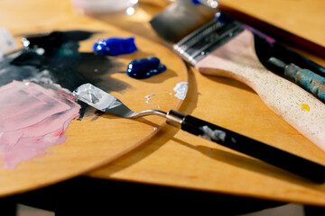 close-up in an art workshop there is a palette on stool palette knife a glass of solvent