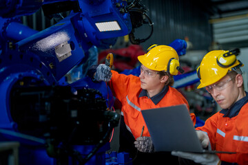 Factory engineers inspecting on machine with smart tablet. Worker works at heavy machine robot arm. The welding machine with a remote system in an industrial factory. Artificial intelligence concept.