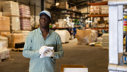 Portrait of focused African-American man checking order list at warehouse