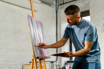 Fototapeta na wymiar in an art studio an artist in blue palette holding in his hands than drawing