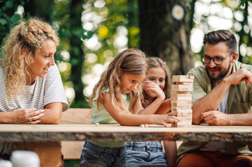 A cheerful family is playing cognitive jenga game in nature.