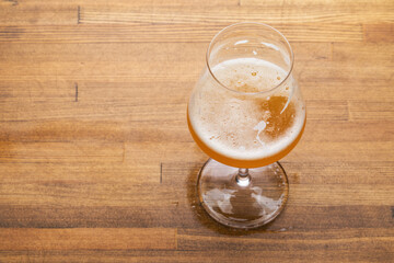 Craft beer in tulip glass on wooden table - obrazy, fototapety, plakaty