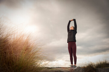 Woman doing stretching exercises outside at sunrise.