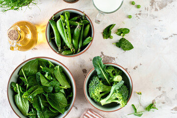 Fresh spinach leaves, green peas, broccoli in a bowl, top view