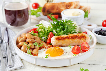 English breakfast. Keto breakfast. Fried egg, beans, chicken sausage and coffee cup.