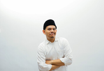 asian muslim man wearing black cap standing while smiling to the camera.