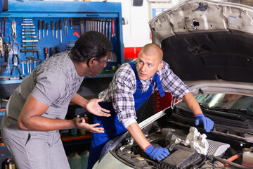 Two car mechanic diagnosing auto engine problem in auto service