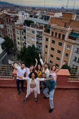 Vertical photo group of friends with wine glasses, smiling and sharing a fun moment on a rooftop...
