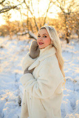 winter walk in the cold. a beautiful blonde girl walks in the park in nature in winter. frosty sunny day.