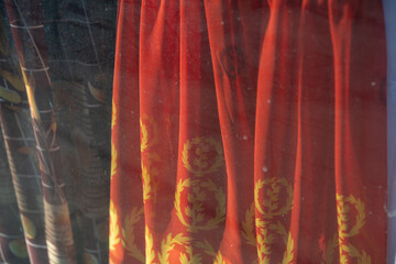 red fabric in a shop window (behind particularly grungy glass)