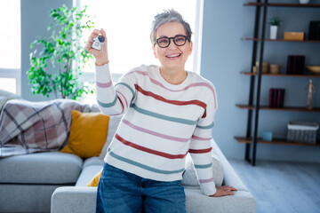 Photo of cheerful positive woman dressed striped sweater eyewear rising new apartment keys indoors...