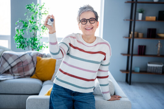 Photo of cheerful positive woman dressed striped sweater eyewear rising new apartment keys indoors house home room