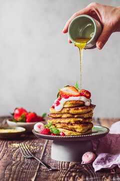 Pancakes with raspberries, pomegranate and yoghurt, pouring honey