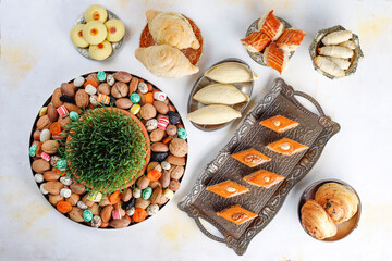 Traditional Azerbaijan holiday Novruz background with green semeni,traditional azerbaijan sweets,shekerbura,qogal,paxlava,mutaki and different nuts and sweets,top view,space for copy
