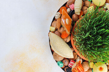 Traditional Azerbaijan holiday Novruz background with green semeni,traditional azerbaijan sweets,shekerbura,qogal,paxlava,mutaki and different nuts and sweets,top view,space for copy