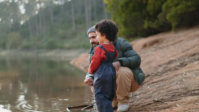 Father and child bonding by the lake, skipping stones together in nature, depicting family time, outdoor activities, and a serene environment.