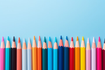 Row of colorful pencils on blue background with copy space