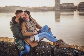 Happy couple embracing while enjoy sitting by the river.