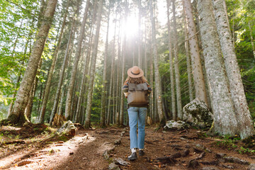 Young woman with backpack walking in beautiful  forest. Hiking and leisure theme.