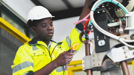 An African professional engineering is fixing or testing the arm of robotic that use in the factory...