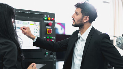 A Professional female engineer and Male CEO are working on PLC Control panel CNC machine. Expertise and technician repairman is maintenance, programming, and improve the automatic innovation machinery