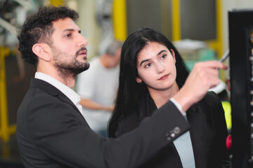 A Professional female engineer and Male CEO are working on PLC Control panel CNC machine. Expertise and technician repairman is maintenance, programming, and improve the automatic innovation machinery