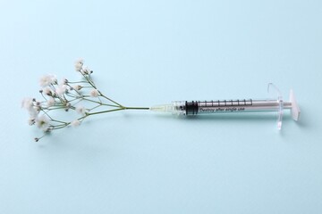 Cosmetology. Medical syringe and gypsophila on light blue background