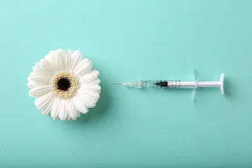 Fotobehang Cosmetology. Medical syringe and gerbera flower on turquoise background, flat lay © New Africa