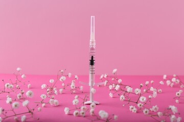 Cosmetology. Medical syringe and gypsophila flowers on pink background