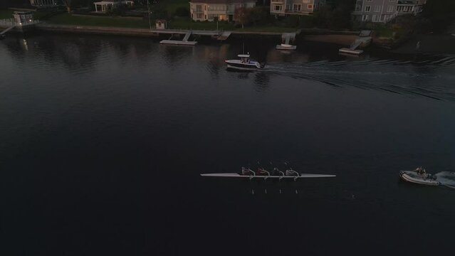 Training of athletes in sports boat rowing. Aerial view of a sport canoe being driven by a team of young women and men in an ocean bay in the evening on calm sea waters in Halifax Harbor, Canada