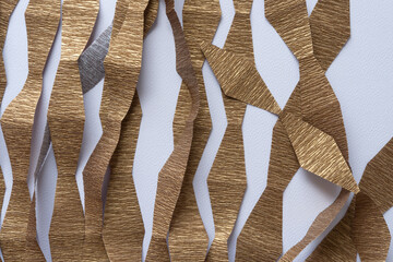 randomly arranged stripes of metallic gold crepe paper stripes with zig zag edges on textured paper