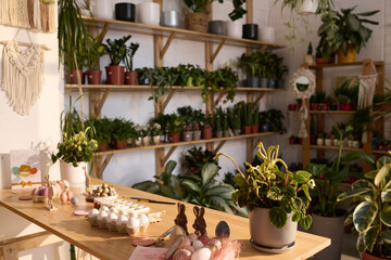 Selective focus wide shot of eggs and decorations for easter on table in modern plant shop interior