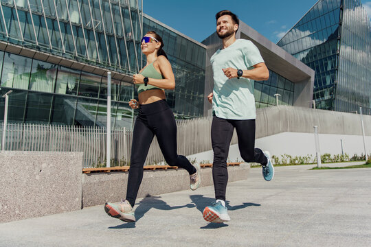Fit couple jogging together in an urban environment, promoting health and companionship.