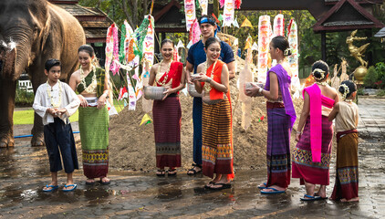 Group of Thai people in colorful traditional Thai costumes holding silverware bowls full of water...