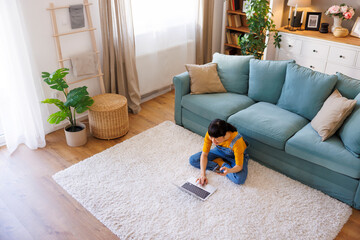 Woman working remotely from home using laptop computer and smart phone